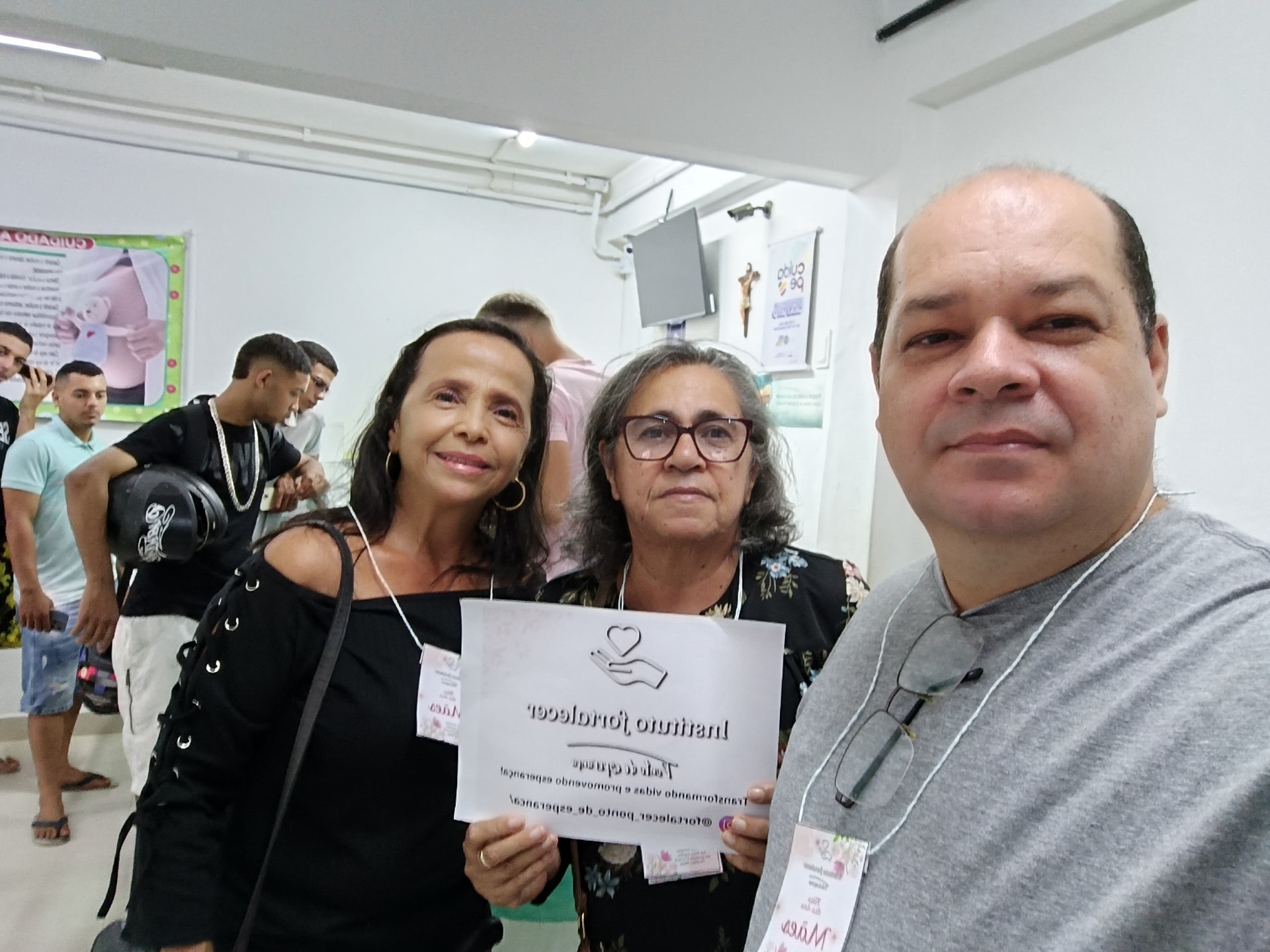 Voluntárias e voluntário do Instituto Fortalecer segurando cartaz do instituto em evento comunitário