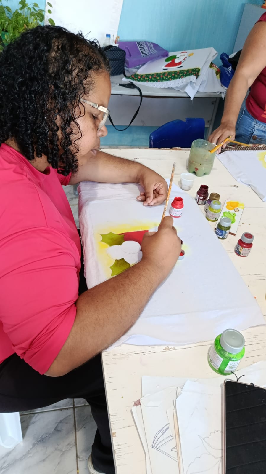Participante pintando um pano de prato durante oficina de pintura em tecido