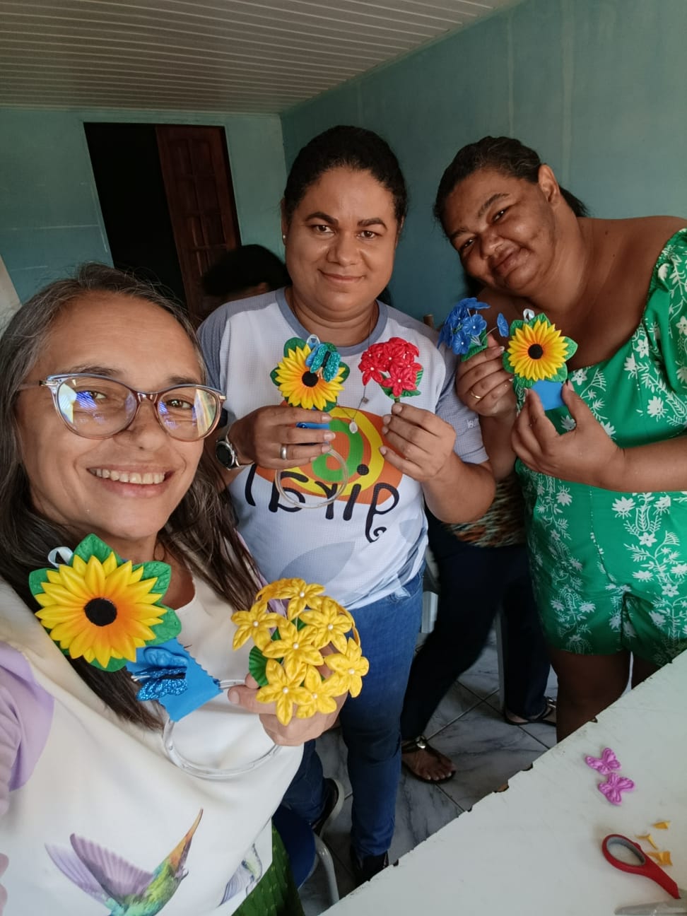 Participantes da oficina de artesanato exibindo flores de EVA feitas à mão